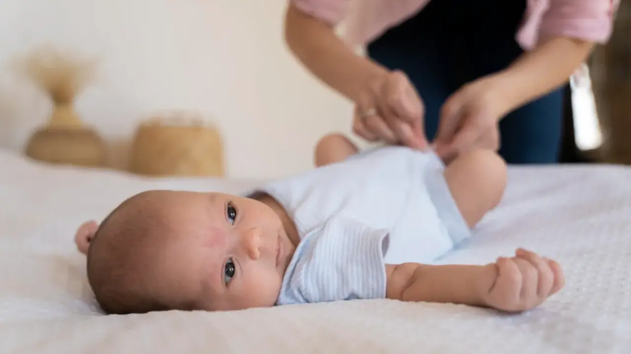 Malutkie dziecko leży na białym kocyku. Mama przygotowuje się do szczepienia RSV w ciąży, by chronić maluszka.