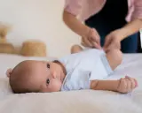 Malutkie dziecko leży na białym kocyku. Mama przygotowuje się do szczepienia RSV w ciąży, by chronić maluszka.