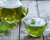 Aromatic melisa w szklanej filiżance i dzbanku, z gałązką świeżej melisy. Czy melisa obniża ciśnienie? Warto spróbować.