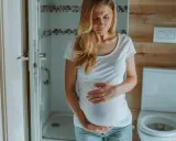 Kobieta w ciąży trzyma się za brzuch, zmartwiona. Czy na początku ciąży boli brzuch jak przy okresie?