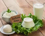 Serek wiejski, kulka sera i szklanka mleka na drewnianym stole. Etykieta "lactose free" wyjaśnia, co to jest laktoza – cukier mleczny, którego tu nie znajdziemy.