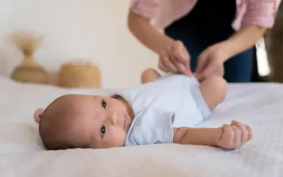 Malutkie dziecko leży na białym kocyku. Mama przygotowuje się do szczepienia RSV w ciąży, by chronić maluszka.