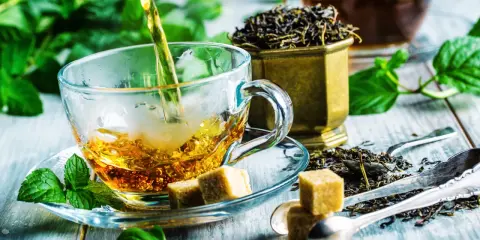 Czy zielona herbata obniża ciśnienie? Zaparzona w szklanej filiżance, z kostkami cukru i świeżą miętą, kusi aromatem.