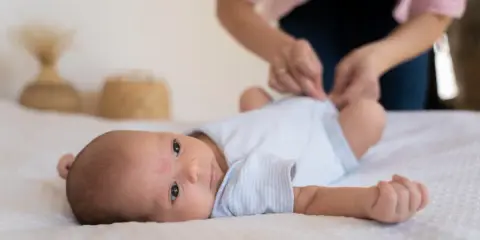 Malutkie dziecko leży na białym kocyku. Mama przygotowuje się do szczepienia RSV w ciąży, by chronić maluszka.