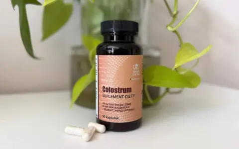 Suplement diety Colostrum w kapsułkach. Dowiedz się, colostrum co to jest i jak działa. W tle zielone liście.