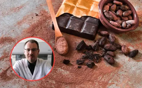 Czy gorzka czekolada jest zdrowa? Naukowiec w białym fartuchu analizuje ziarna kakao, tabliczkę gorzkiej czekolady i kakao w proszku.