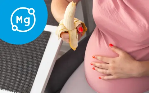 Ciężarna kobieta je banana, symbolizującego magnez w ciąży.