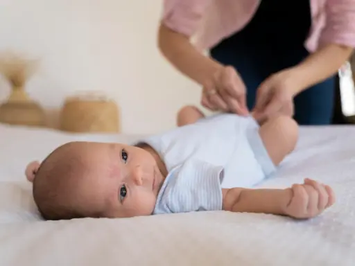 Malutkie dziecko leży na białym kocyku. Mama przygotowuje się do szczepienia RSV w ciąży, by chronić maluszka.