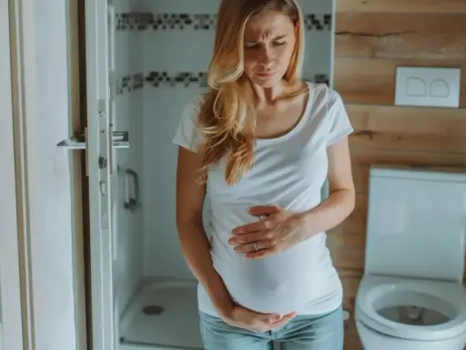 Kobieta w ciąży trzyma się za brzuch, zmartwiona. Czy na początku ciąży boli brzuch jak przy okresie?