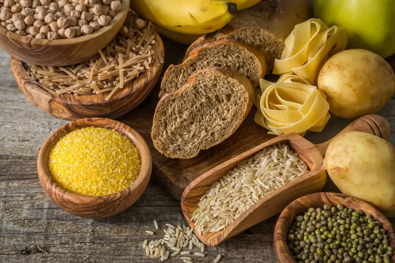 Różnorodne produkty bogate w węglowodany: ciecierzyca, makaron, ryż, chleb, ziemniaki, kukurydza i fasolka mung.