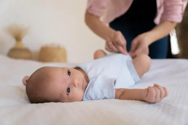 Malutkie dziecko leży na białym kocyku. Mama przygotowuje się do szczepienia RSV w ciąży, by chronić maluszka.